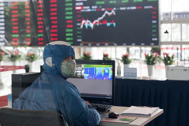 A worker wearing a protective suit reacts in front of an infrared temperature machine in the lobby of the Shanghai Stock Exchange building in Shanghai, China. Picture: (AP Photo)