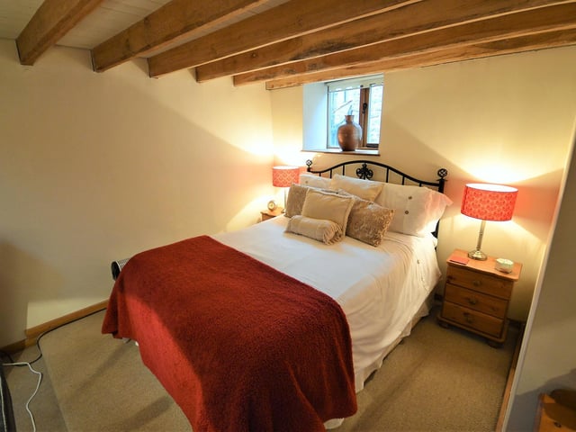 A more cosy double bedroom, with character beams and window.