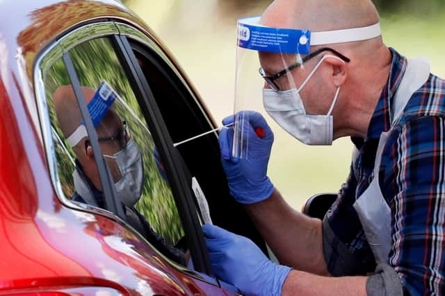 A medical worker takes a swab to test for the novel coronavirus (Photo by Adrian DENNIS / AFP) (Photo by ADRIAN DENNIS/AFP via Getty Images) PPP-200527-172926003