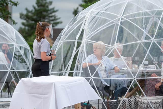 A waitress takes orders from the outdoor dining pods which have been installed for social distancing at The Barn Restaurant, Terrington St John. Picture: Joe Giddens/PA Wire