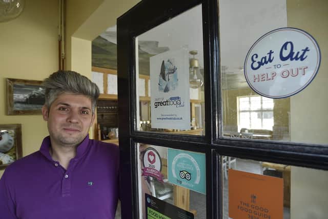 Damian Wawrzyniak with his Eat Out To Help Out sign at his restaurant House of Feasts at Eye. EMN-200728-181516009