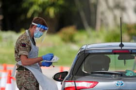 A member of the armed forces takes a swab to test for the novel coronavirus COVID-19 from a visitor to a drive-in testing facility  (Photo by ADRIAN DENNIS/AFP via Getty Images) PPP-200527-172902003