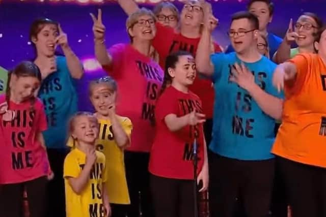 Sam, in the blue shirt, with his mum Lesley on his left in the pink shirt on stage at their first audition