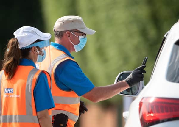 Staff scan the barcode on a coronavirus test through a car window at a mobile Covid-19 testing centre in Peterborough. Picture Joe Giddens/PA Wire.