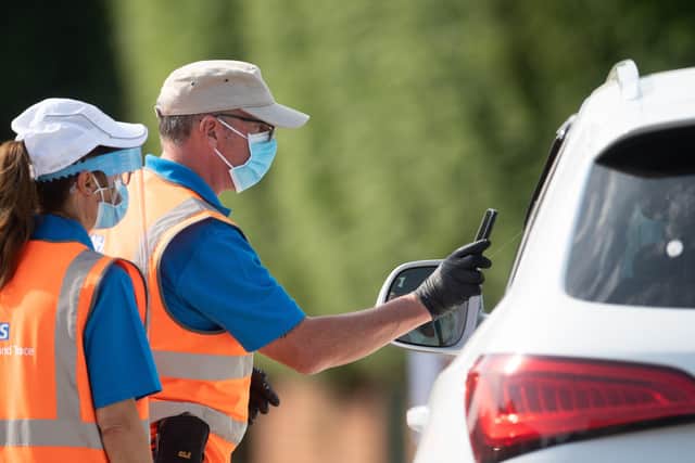 Staff scan the barcode on a coronavirus test through a car window at a mobile Covid-19 testing centre in Peterborough.