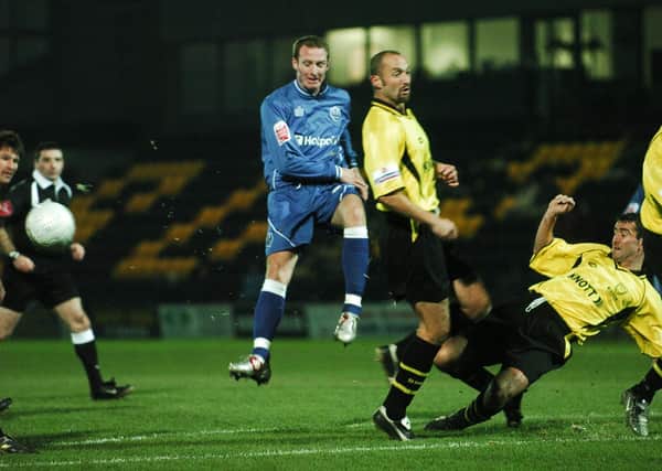 Peter Gain (blue) in action for Posh at Burton Albion in a first round FA Cup replay.