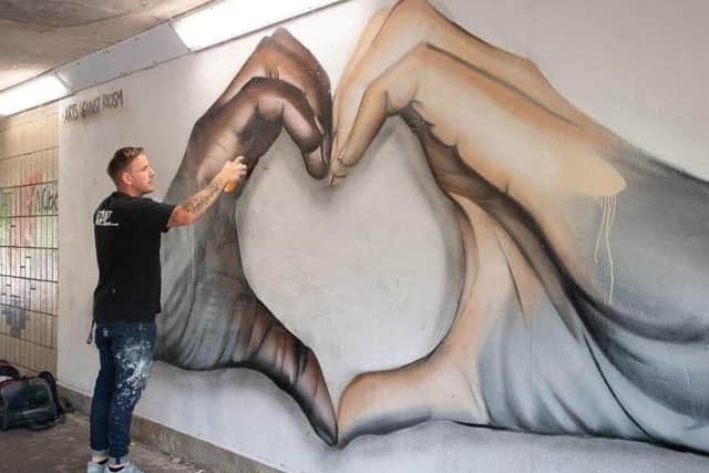 Street artist Nathan Murdoch touches up his anti-racism. Photo: Joe Giddens/PA Wire EMN-200206-151710005