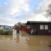 People wade through floodwater to check boats and property at Orton as the area is completed flooded as the River Nene burst its banks in Peterborough, Cambridgeshire. Picture: Paul Marriott.