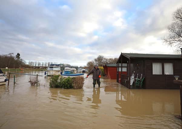 People wade through floodwater to check boats and property at Orton as the area is completed flooded as the River Nene burst its banks in Peterborough, Cambridgeshire. Picture: Paul Marriott.