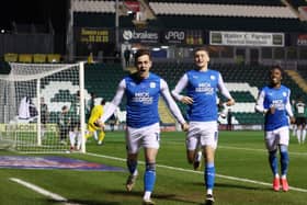 Sammie Szmodics (left) celebrates his goal for Posh at Plymouth with Jack Taylor and Siriki Dembele (right).