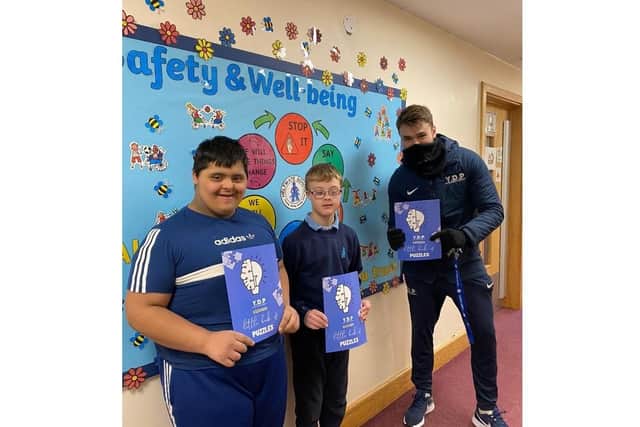 Luke Kennedy handing out puzzle books to Heltwate School.