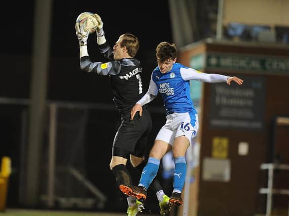 Posh teenager Harrison Burrows challenges Pompey goalkeeper Craig MacGillivray (Pictured: David Lowndes)