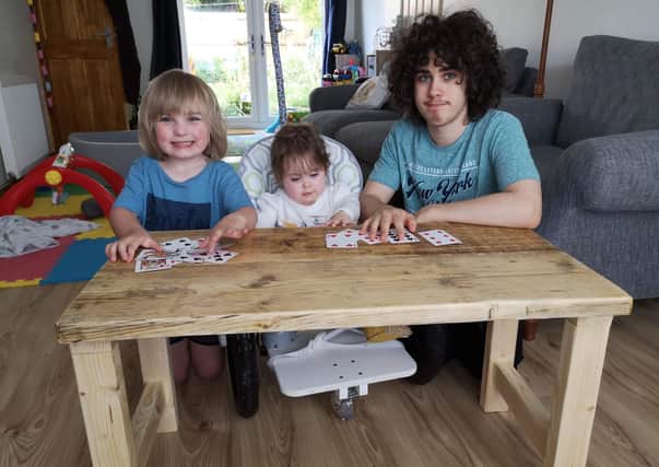 Charlotte is able to play with brothers Timothy, left, and Kenzie at the specially designed desk.