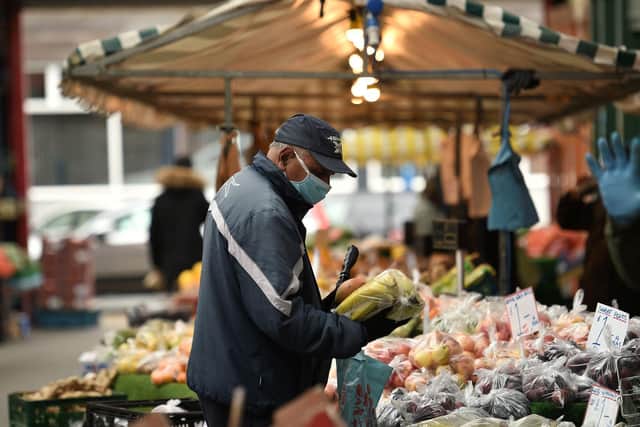 A shopper wears a facemask as he chooses produce at an open air market (Photo by Oli SCARFF / AFP) (Photo by OLI SCARFF/AFP via Getty Images)
