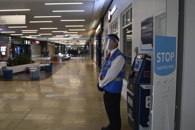 A member of Queensgate staff in protective face shield and gloves as non-essential shops re-open. EMN-200615-114900009