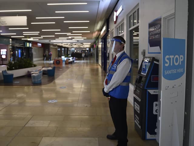 A member of Queensgate staff in protective face shield and gloves as non-essential shops re-open. EMN-200615-114900009