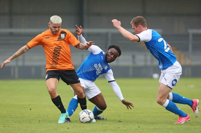 Posh youngster Hameed Ishola (blue) scored for Yaxley at Lowestoft.