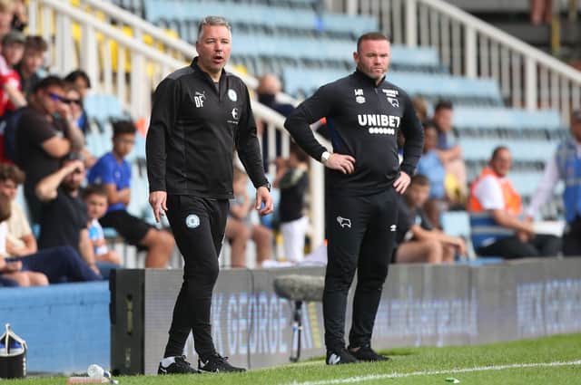 Derby manager Wayne Rooney (right) alongside Posh boss Darren Ferguson.