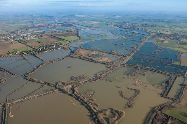 View of 2014 flooding of the Great Ouse River over Fen Drayton looking northeast towards Holywell. The isolated circular mound of a round barrow, a Bronze Age burial site, is visible surrounded by the flood waters in the foreground. (Photo: Historic England)