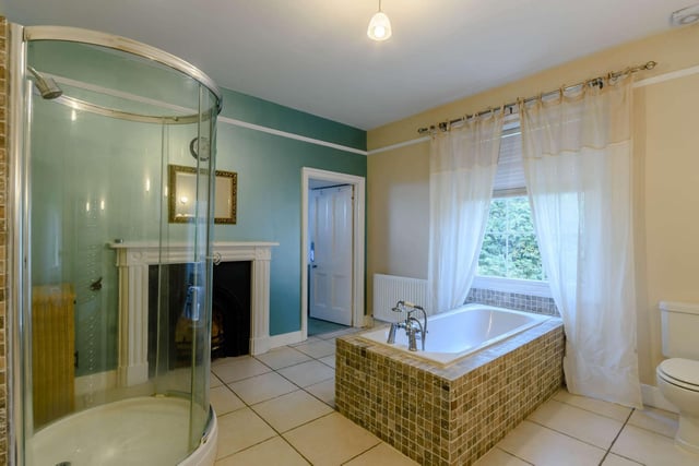 The family bathroom has a wide window and a pretty cast iron fireplace with painted mantelpiece.