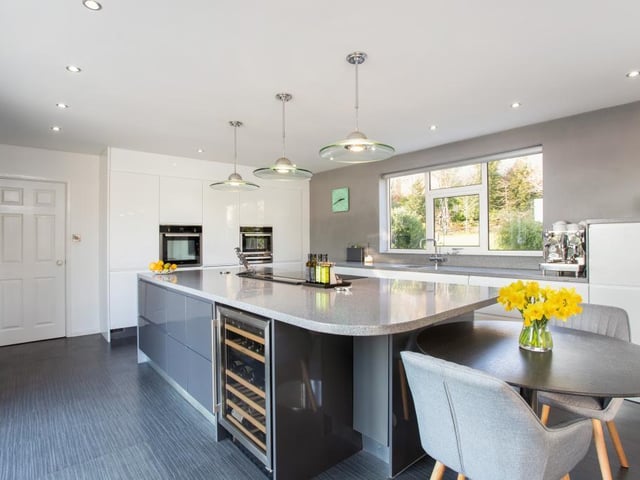 The kitchen has a central island and integrated appliances, including a wine fridge.