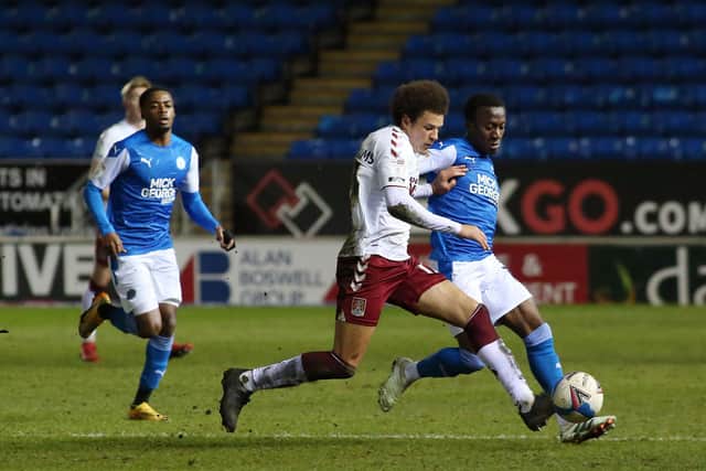 Siriki Dembele of Peterborough United in action with Shaun McWilliams of Northampton Town. Photo: Joe Dent/theposh.com.