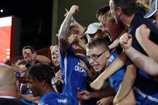 Jason Cummings is mobbed by Posh fans after scoring a late winner at Charlton.
