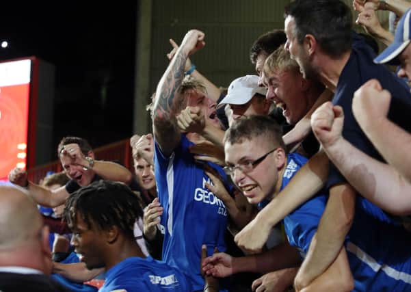 Jason Cummings is mobbed by Posh fans after scoring a late winner at Charlton.