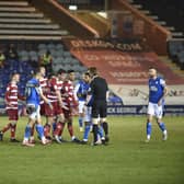 Doncaster players surround referee Scott Oldham demanding that Posh centre-back Frankie Kent is sent off late in the match. Photo: David Lowndes.
