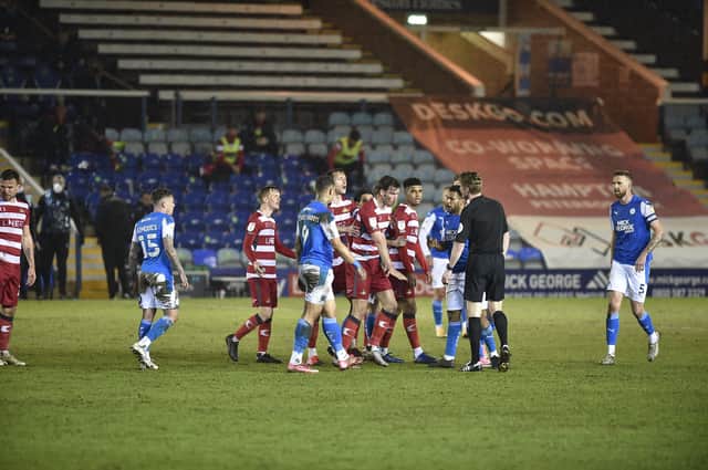 Doncaster players surround referee Scott Oldham demanding that Posh centre-back Frankie Kent is sent off late in the match. Photo: David Lowndes.