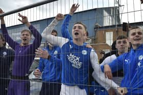 Posh players Jack Taylor (right) and Josef Bursik behind the wire fencing after winning promotion from League One. Photo: David Lowndes.