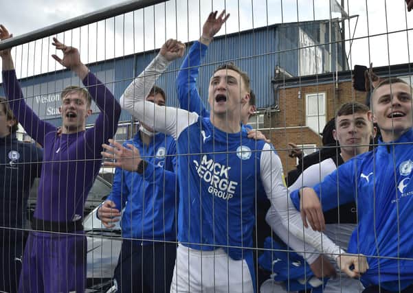 Posh players Jack Taylor (right) and Josef Bursik behind the wire fencing after winning promotion from League One. Photo: David Lowndes.