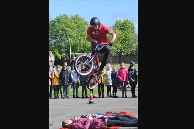 Mike Mullen performs a BMX jump over three members of staff.