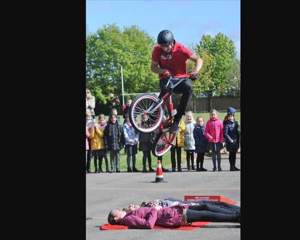 Mike Mullen performs a BMX jump over three members of staff.