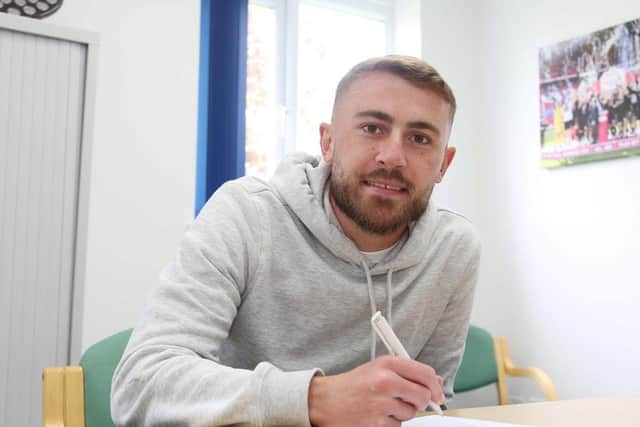Dan Butler signs his new Posh contract. Photo: Joe Dent/theposh.com.