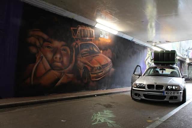 Cain's skid car alongside his mural.