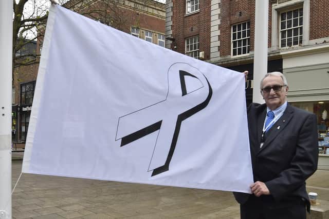 Former city council leader John Holdich raising the White Ribbon flag outside the Town Hall