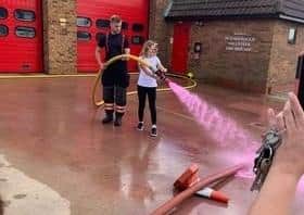 Amelia helps withe the hose spraying pink water.