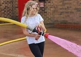 Amelia helps withe the hose spraying pink water.