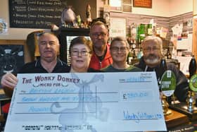 Wonky Donkey  owners Steve, Andrew, Dave and Carol Williams hand over a cheque to Sandy Foster from the Royal British Legion following the sale of the Great Uncle Tom beer