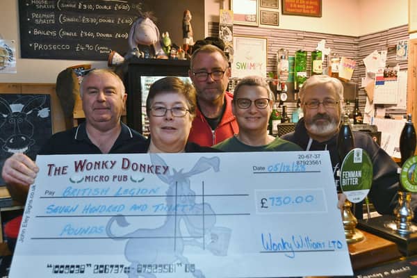 Wonky Donkey  owners Steve, Andrew, Dave and Carol Williams hand over a cheque to Sandy Foster from the Royal British Legion following the sale of the Great Uncle Tom beer