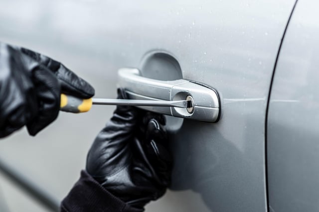 A car thief hands trying to steal a vehicle with screwdriver