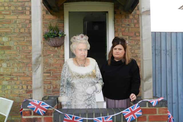 Katie Howard pictured with a life-size cut-out of Elizabeth II who stands proudly on her front porch, which is decked with Union Flag bunting.