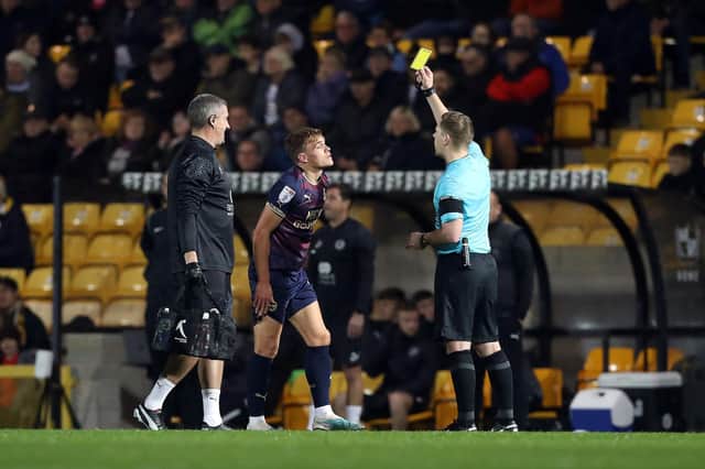Archie Collins of Peterborough United is shown a yellow card at Port Vale by referee Marc Edwards. Photo: Joe Dent/theposh.com