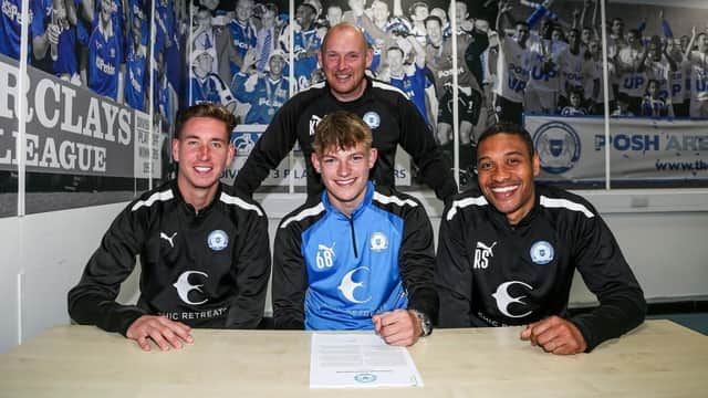 Ben Challinor signs his Posh contract watched by club Academy staff. Photo: Joe Dent/theposh.com.