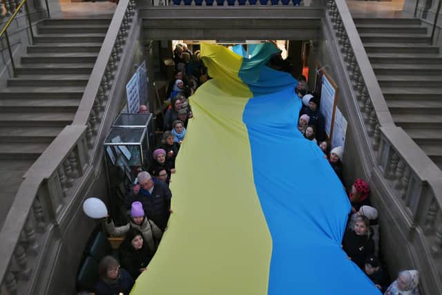 Ukrainians with a large flag in the town hall during a vigil one year on from the start of Russia's invasion.