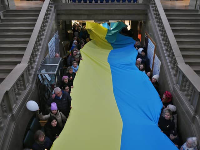 Ukrainians with a large flag in the town hall during a vigil one year on from the start of Russia's invasion.