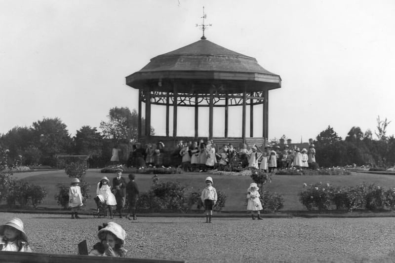 This superb, razor-sharp image shows smartly-dressed children posing for a photo around the bandstand in 1915.