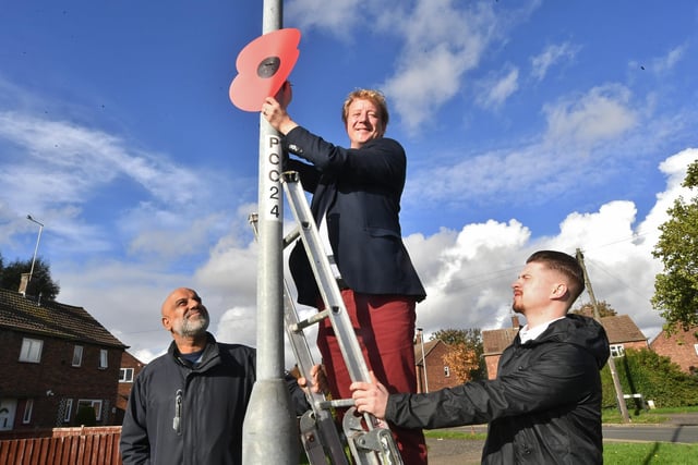 Peterborough MP Paul Bristow putting up giant poppies in Central Avenue, Dogsthorpe with Cllr Ishfaq Hussain and party worker Benjamin O'Hara.