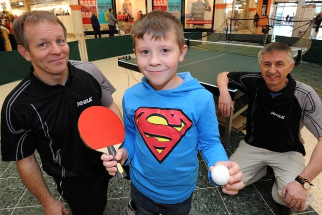 Rhys Young, 8, from Whittlesey, tries table tennis at Serpentine Green during a recruitment drive by Hampton Table Tennis Club members (left) John Morris and (right) chairman Robin Wilkin.
